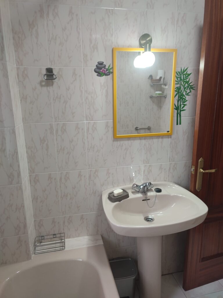 Baño de la planta baja con espejo, lavabo y bañera en la casa rural Regajo Lobos