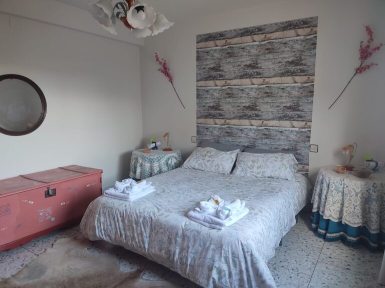 Habitación con cama de matrimonio, espejo, baúl, mesillas y decoración de la casa rural Regajo Lobos