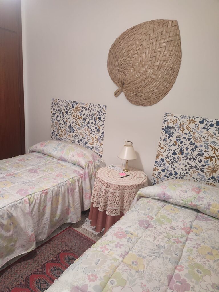 Habitación con dos camas, mesita, lámpara y decoración en la casa rural Regajo Lobos
