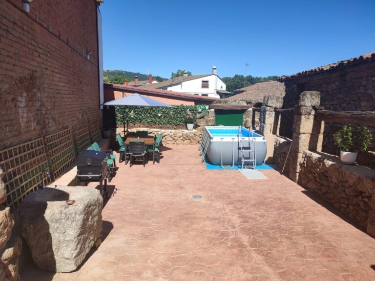 Patio con piscina, barbacoa mesa y sillas en un día soleado en la Casa rural Regajo Lobos